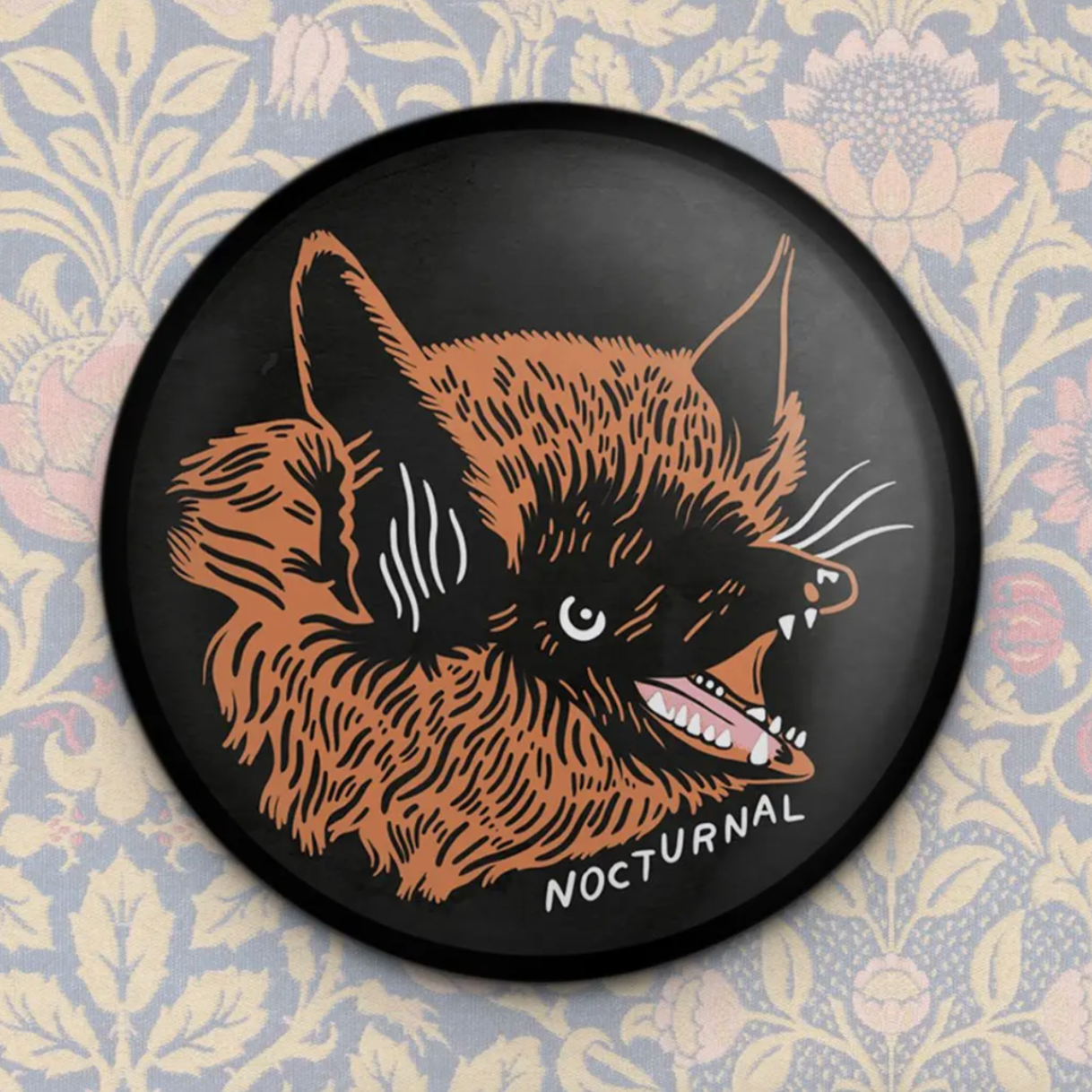 A round magnet featuring an illustration of a bat with the word 'nocturnal' below it.