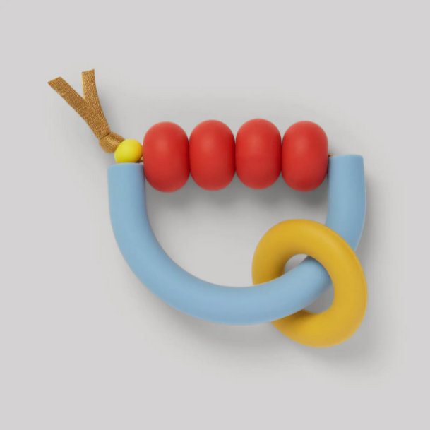 A colorful teething ring with red beads, a blue arch, and a yellow ring, attached to a brown strap.