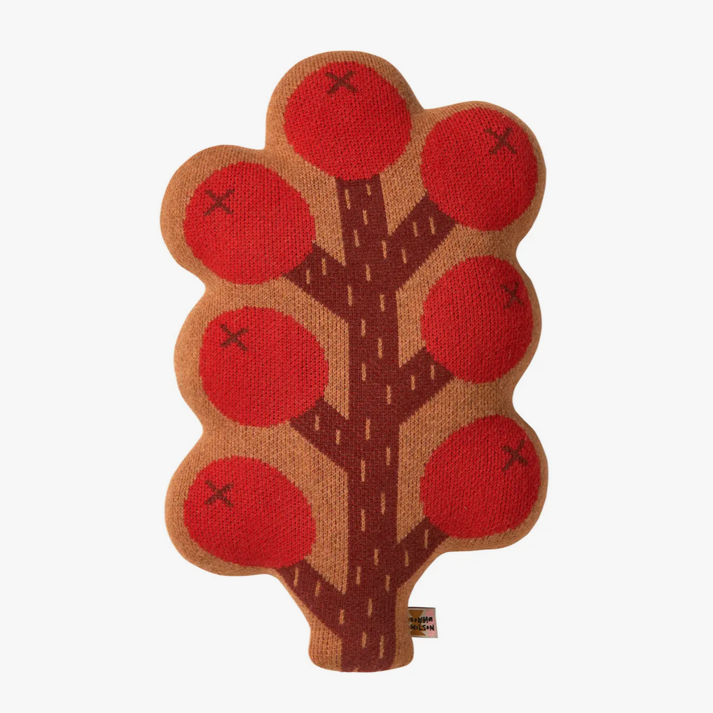A knitted cushion in the shape of a tree with red berry-like fruits on a beige stem and branches.