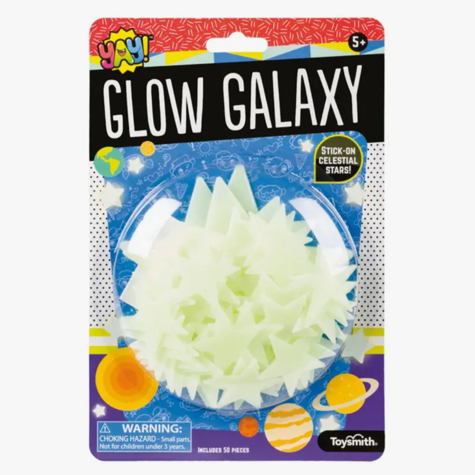 Packaging for 'YAY! Glow Galaxy' showing a blister packet with 50 glow-in-the-dark adhesive star-shaped stickers. The background is decorated with colorful space-themed graphics.
