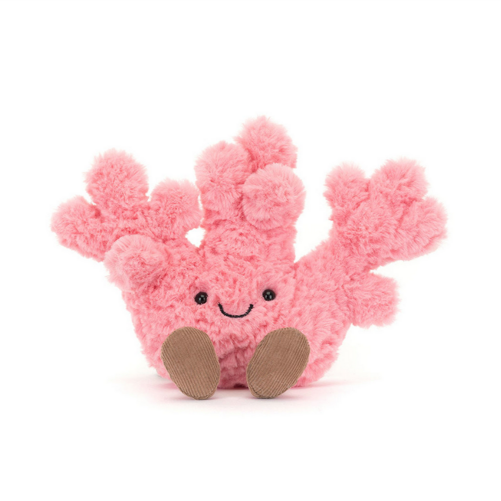 A plush toy resembling a pink coral with a smiling face and brown eyes, with no other distinct objects in the background.