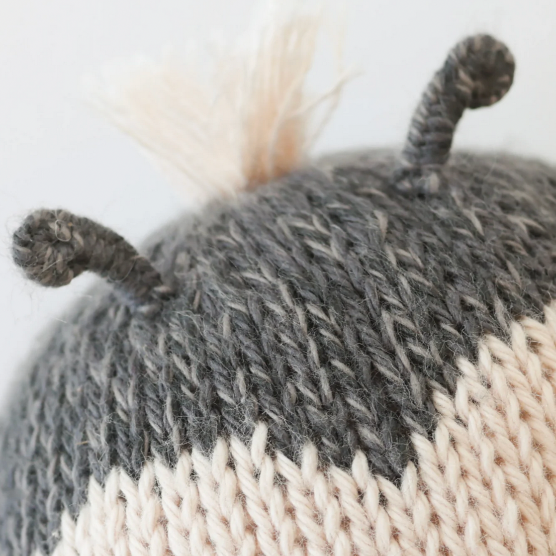 Knitted doll with gray and white pattern on a light background