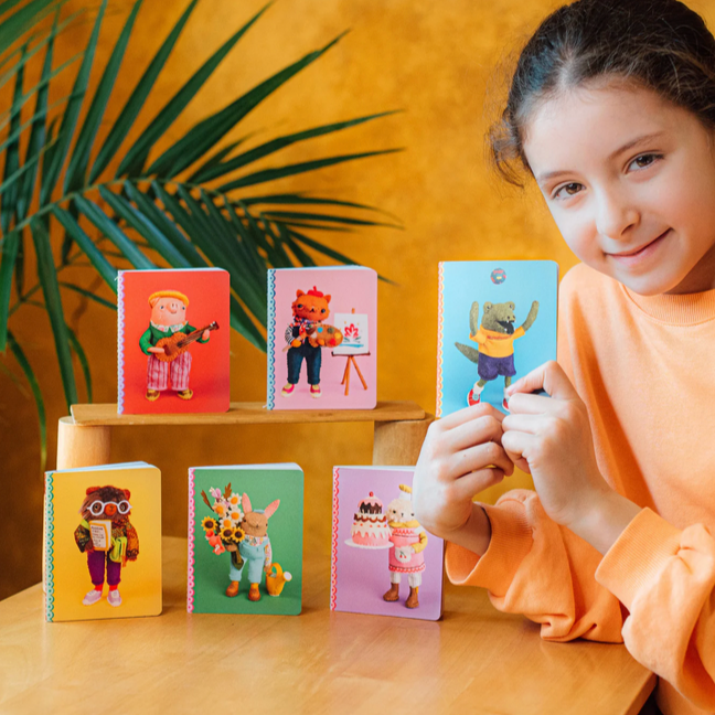 Person holding a colorful card with felted characters on a wooden table.