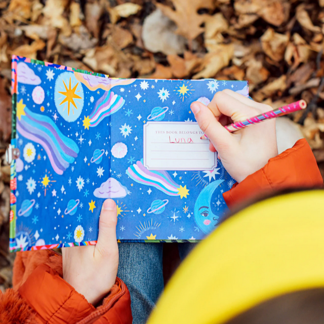 Children's journal with colorful space-themed design held by a child, with a lock and key icon at the bottom.