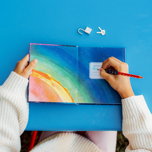 Person holding a colorful notebook with a blue cover against a light blue background