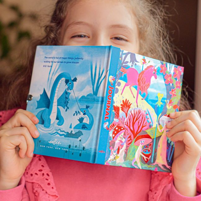 Child holding a colorful book with mermaid and castle illustrations