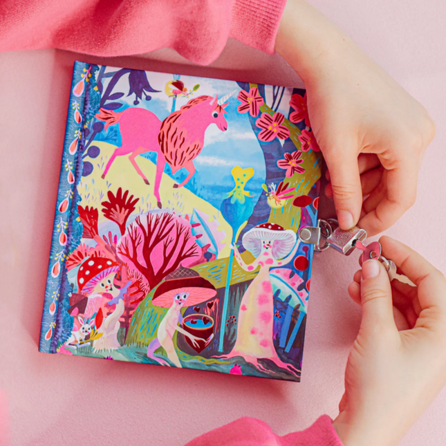 Colorful notebook with unicorn design, being locked by a hand on a pink background.