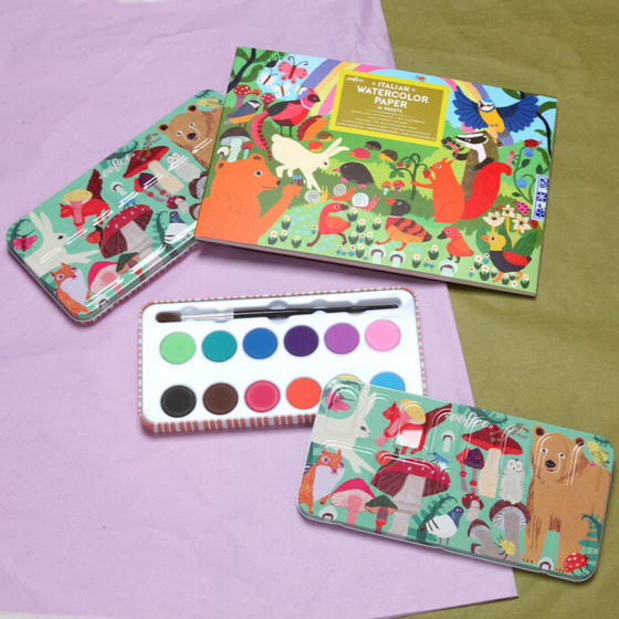 Colorful children's art supplies including watercolor packs and paint palettes on a purple and green background.