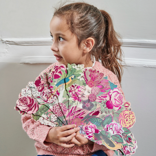 Child holding a colorful floral fan against a neutral background