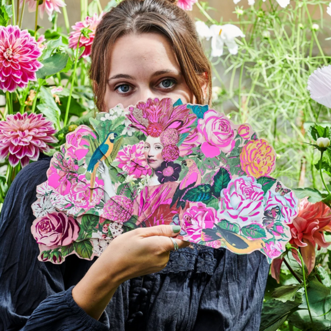 Woman holding a floral fan in a garden setting