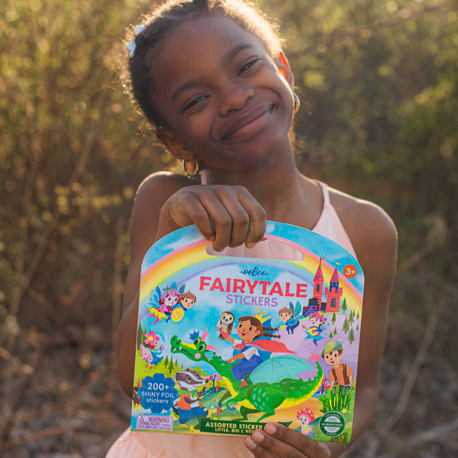 Child holding a fairytale stickers book outdoors