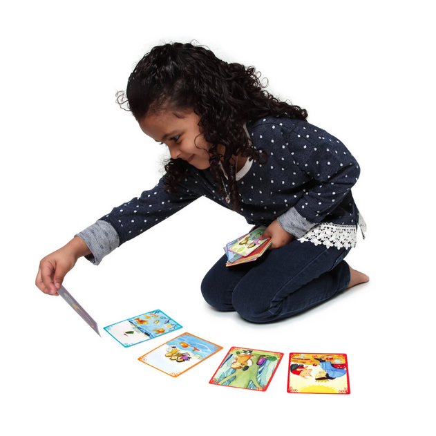 Child playing with a story card game on the floor