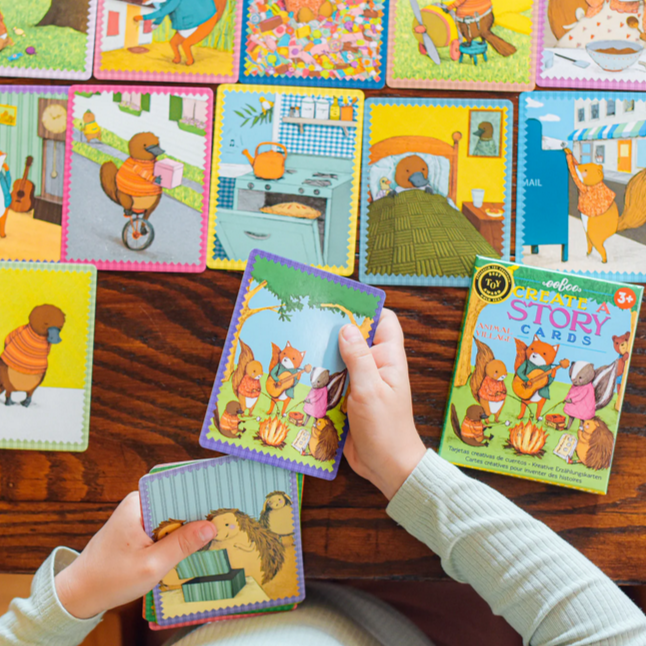 Child playing with colorful story cards on a wooden table