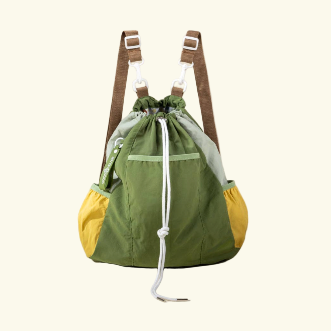 Green drawstring bag with brown straps on a beige background