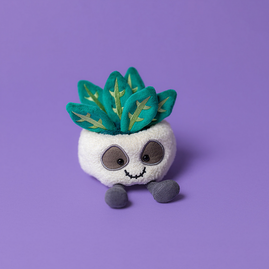 Plush toy resembling a skull with plant on a purple background