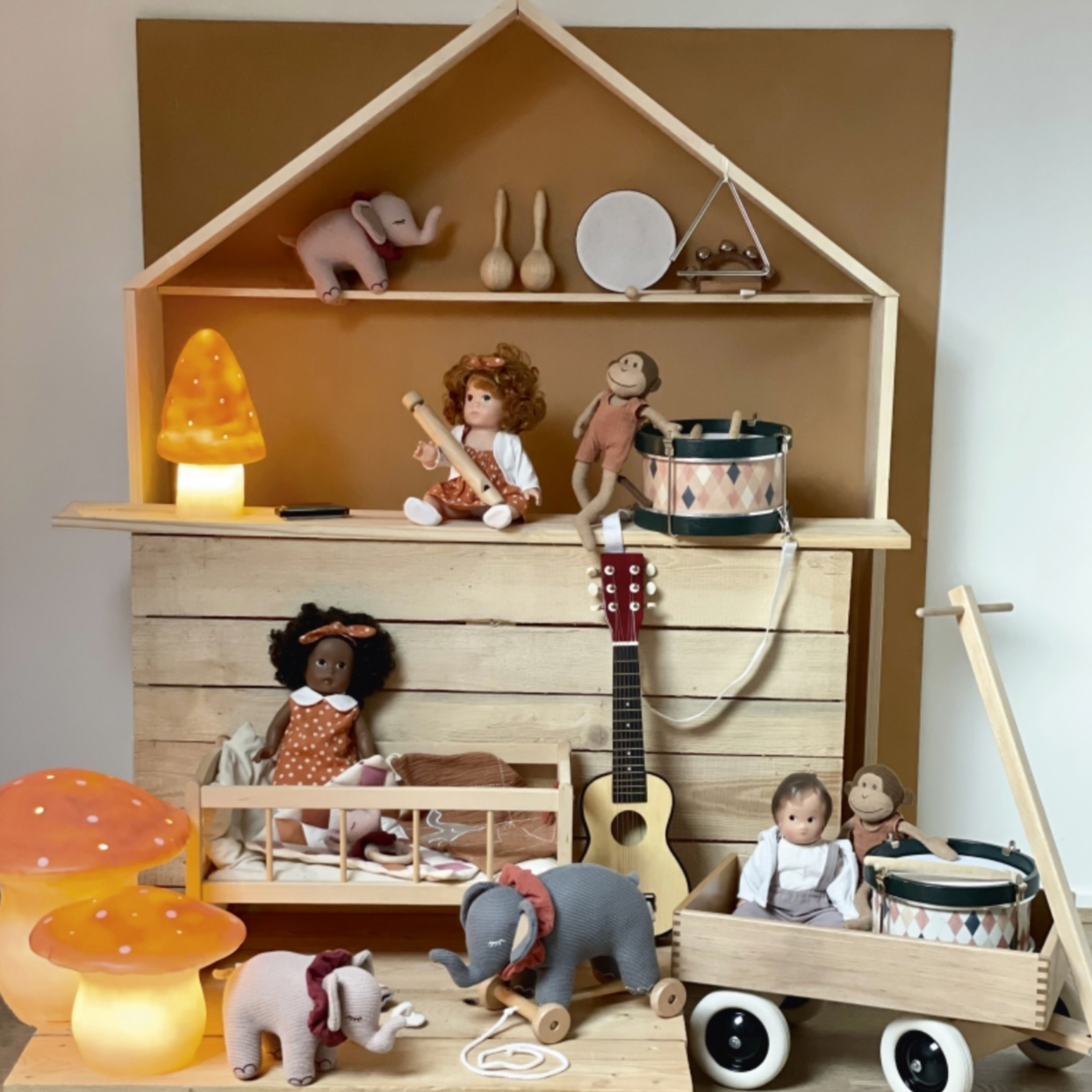 Wooden toy house with various toys on shelves and on the floor.