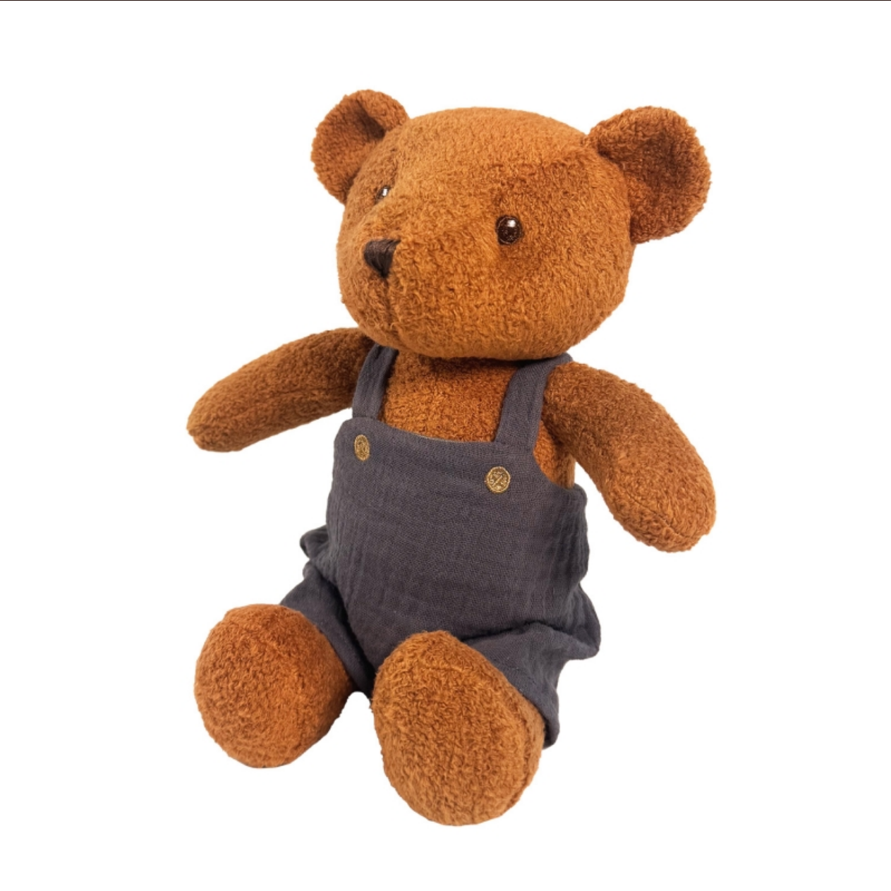 Brown teddy bear wearing gray overalls on a white background