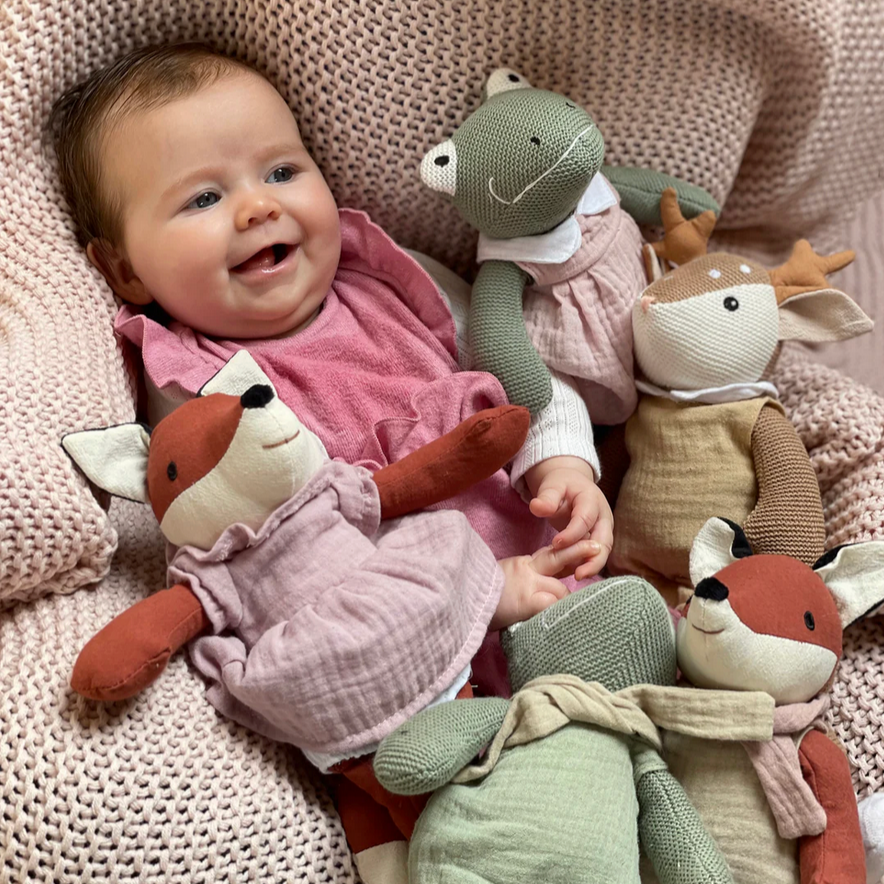 Baby surrounded by plush toys on a soft surface