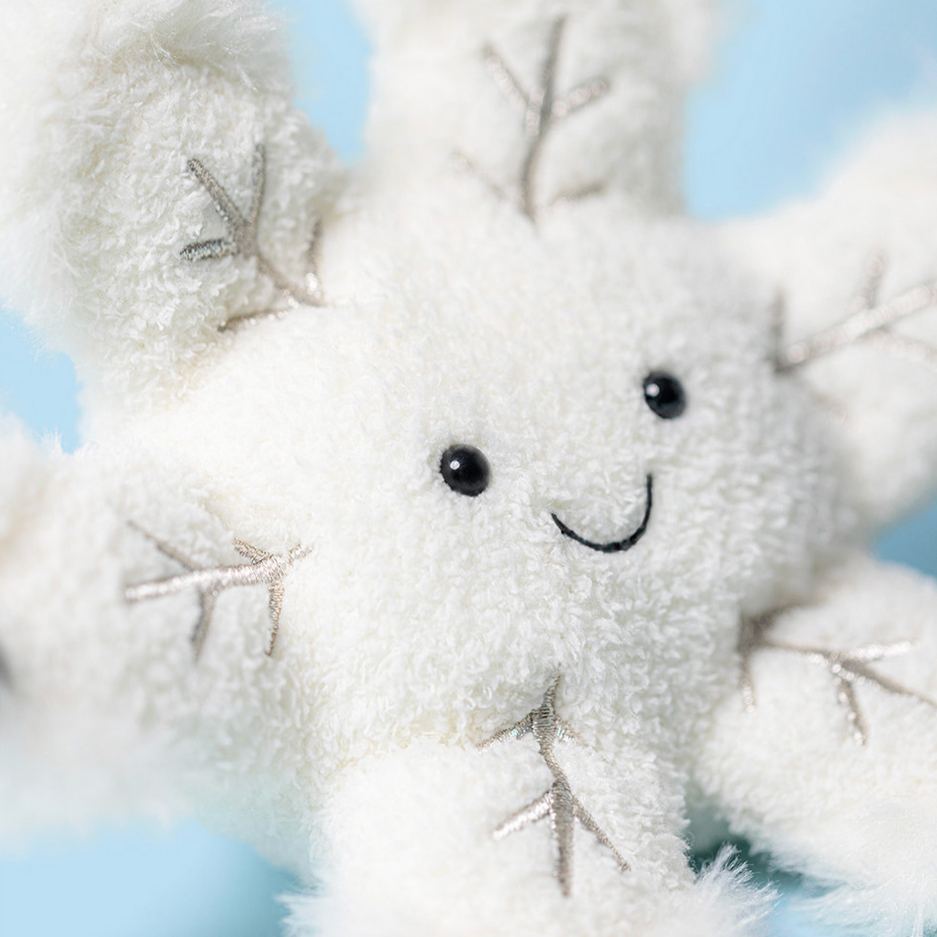 White plush snowflake with a smiling face against a blue sky background