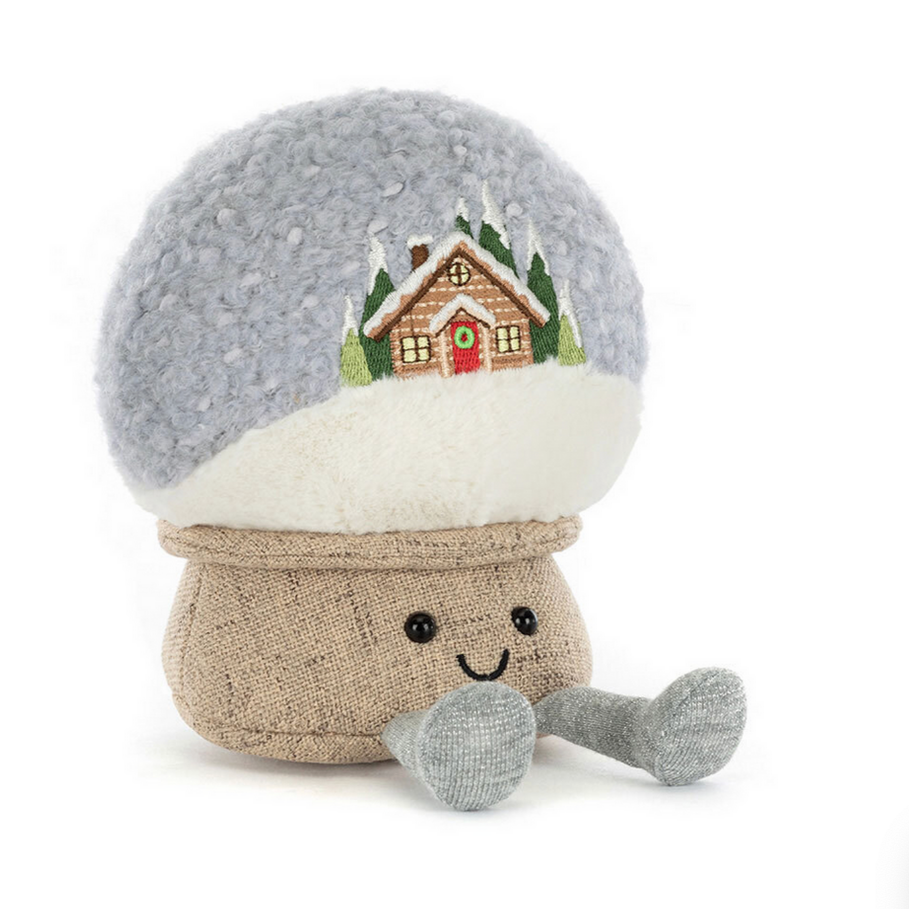 Stuffed snowglobe toy with a snow globe design featuring a house and trees on a white background