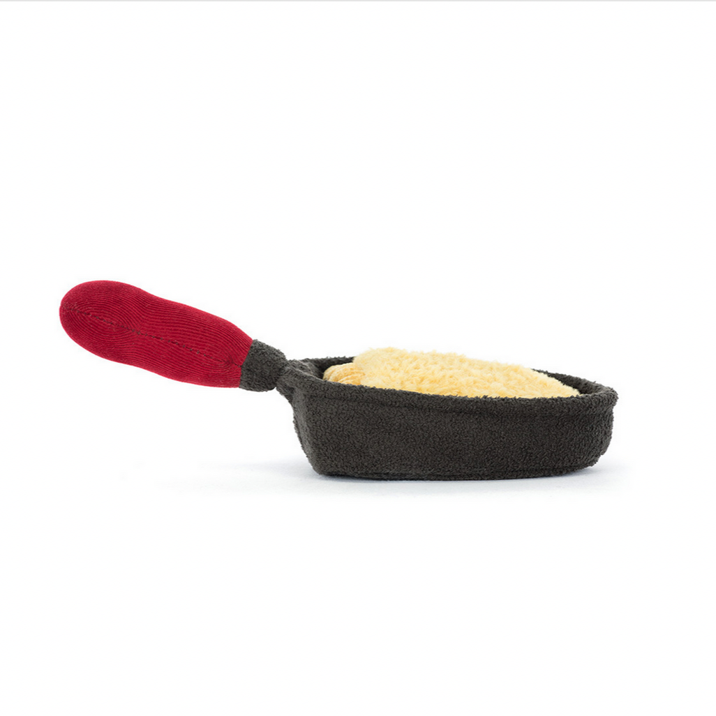 Miniature frying pan with red handle filled with food on a white background