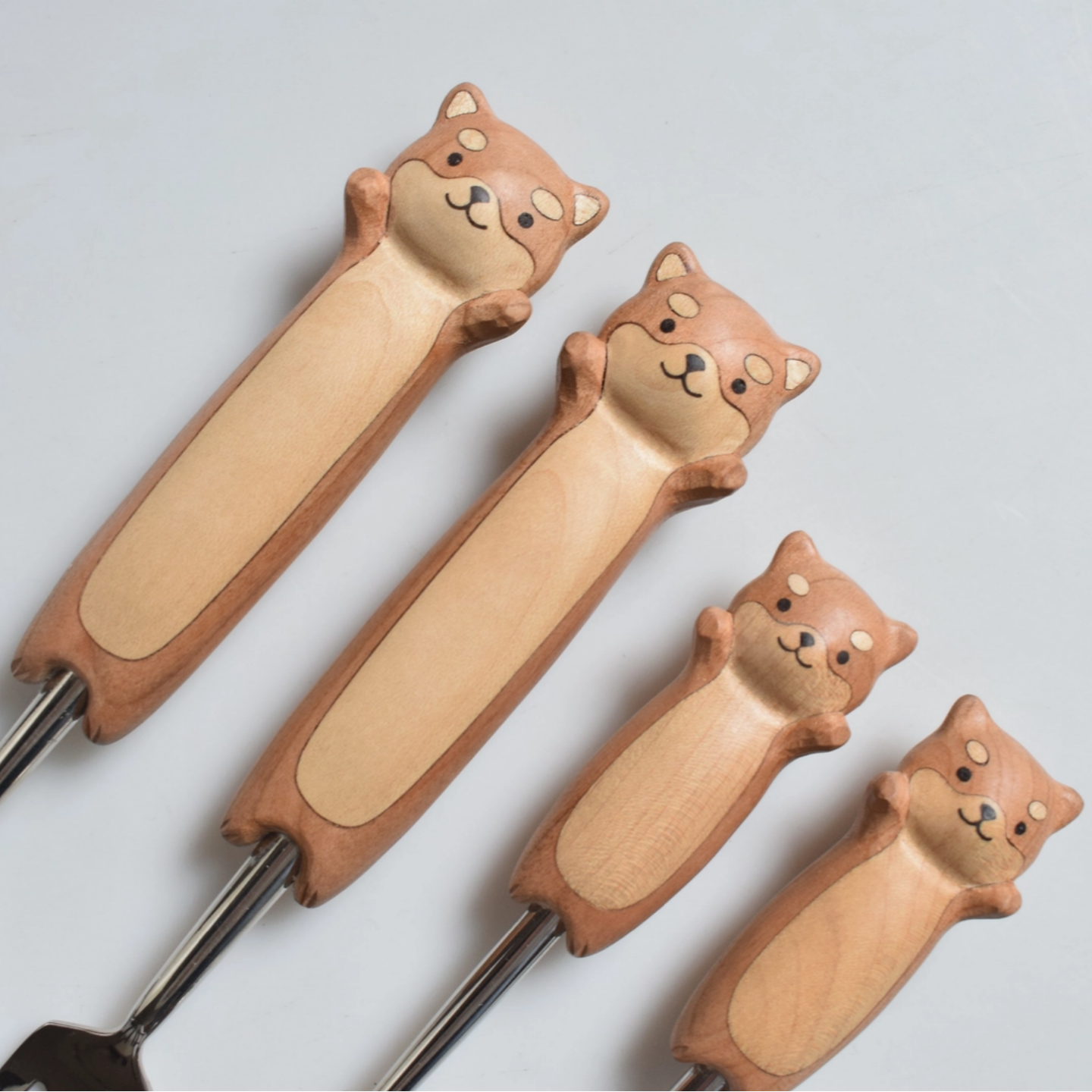 Set of four dog-shaped utensils on a light gray background