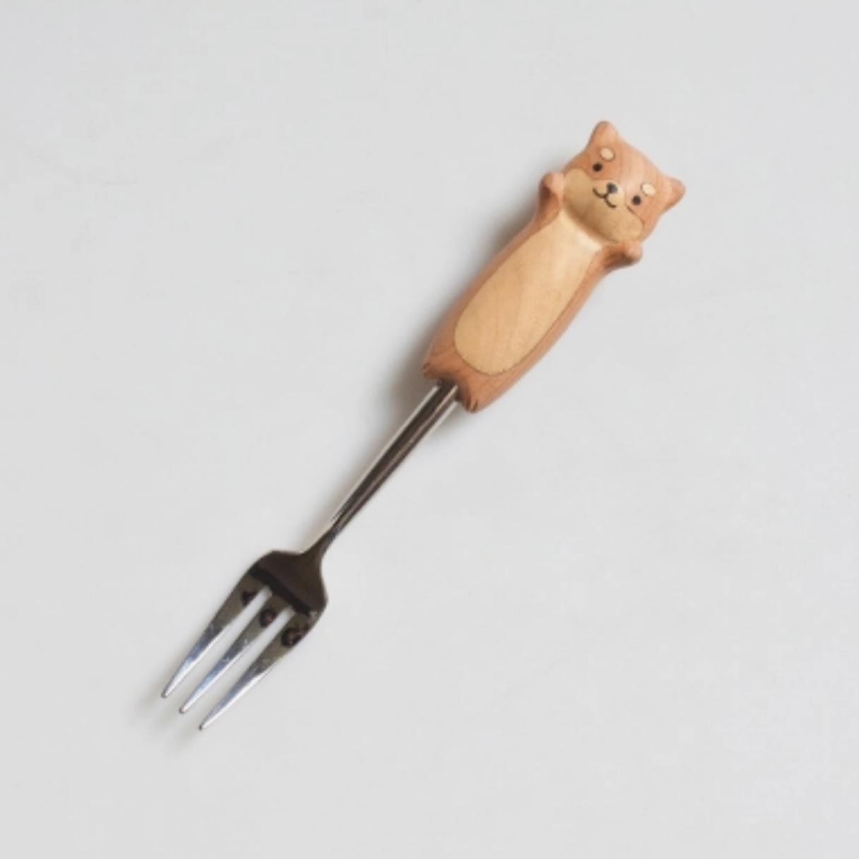 Fork with a dog-shaped wooden handle on a light gray background