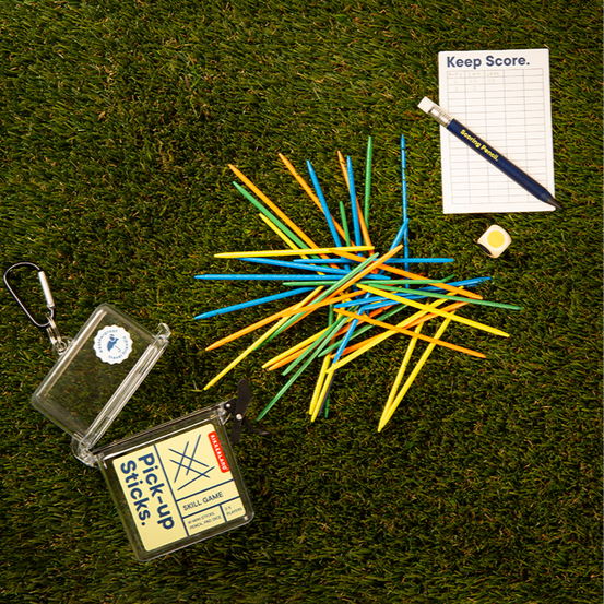 Colorful pick-up sticks on grass with a carrying case and scorecard.