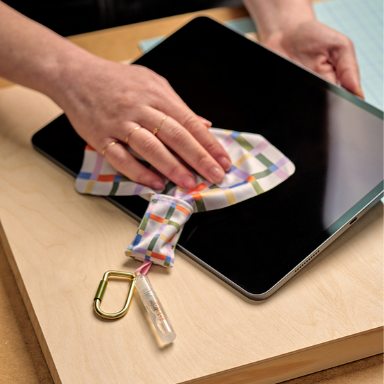 Colorful cloth with a carabiner attached cleaning a tablet on a wooden surface