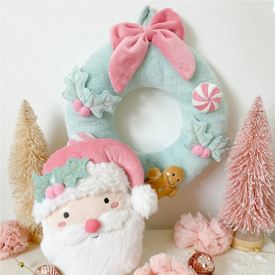Decorative wreath with a Santa Claus face, pink bow, and candy decorations on a white background.