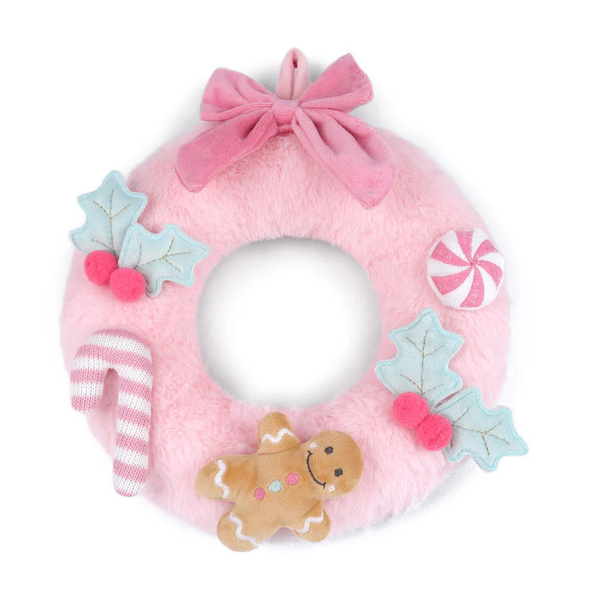 Pink plush wreath with gingerbread man, candy cane, and star decorations on a white background