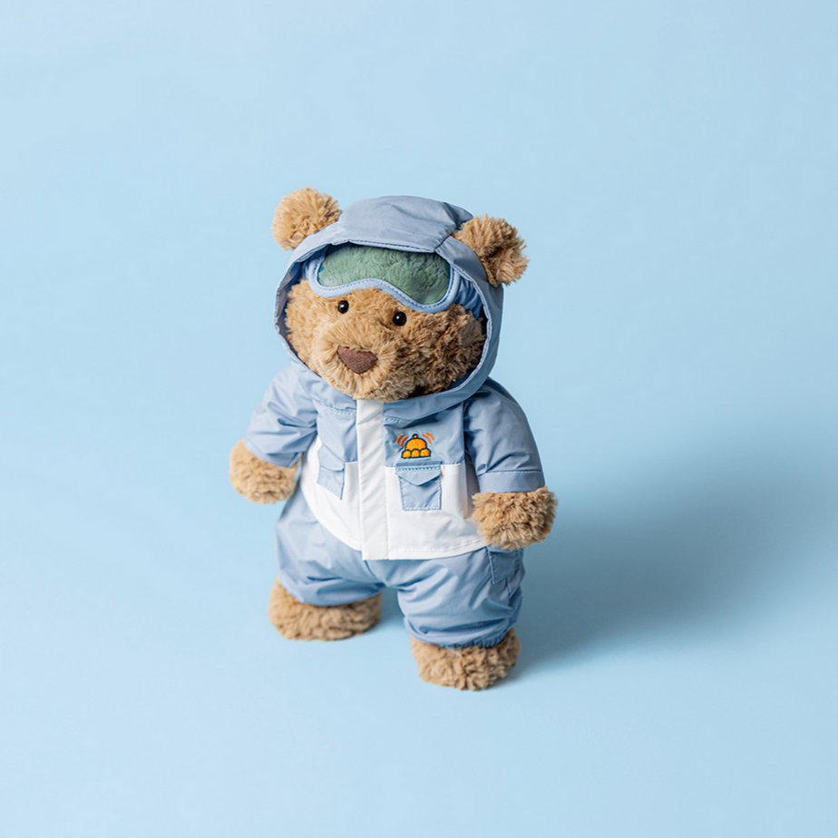 Stuffed teddy bear wearing a blue astronaut suit on a light blue background