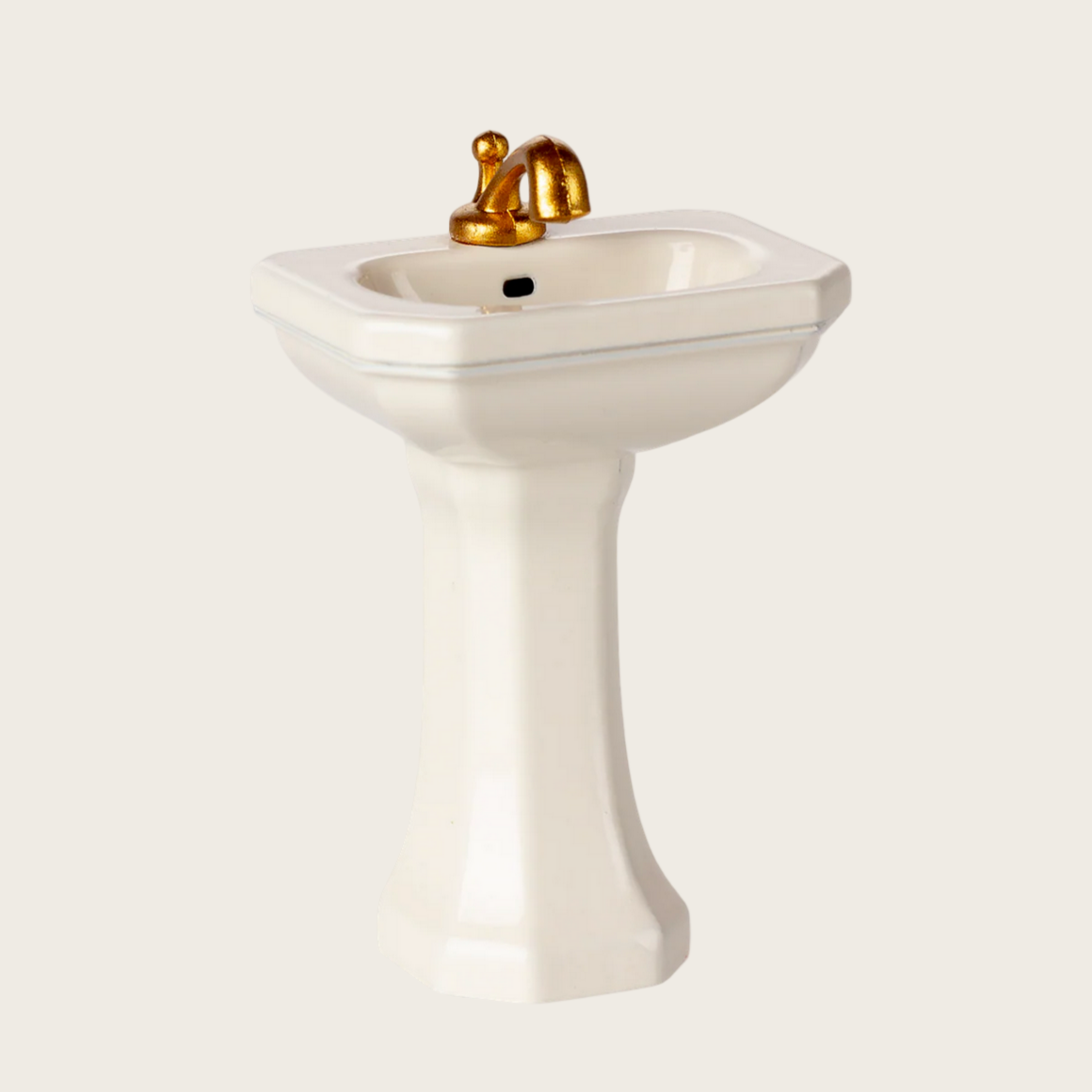 White pedestal sink with gold faucet on a white background