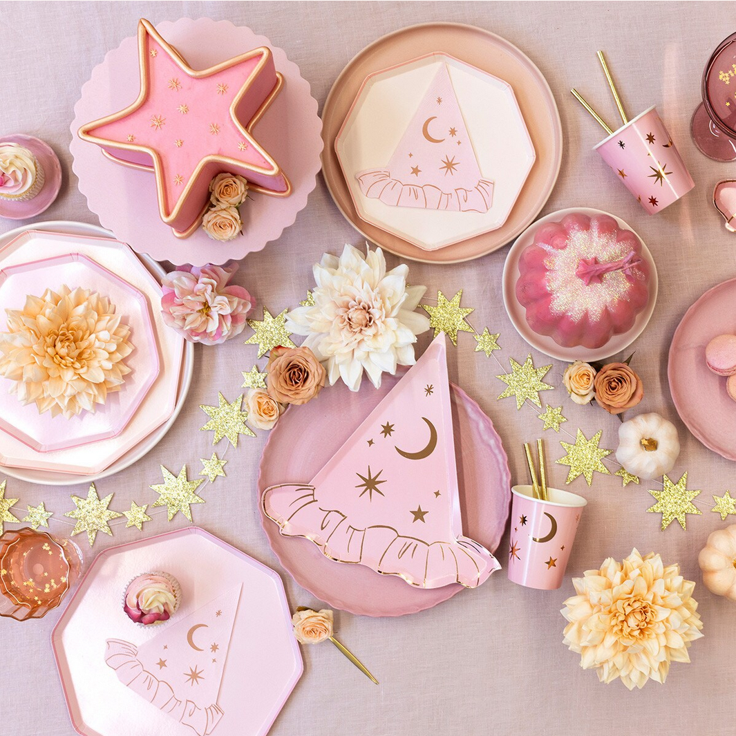 Pink party hats, plates, and decorations with flowers on a light background