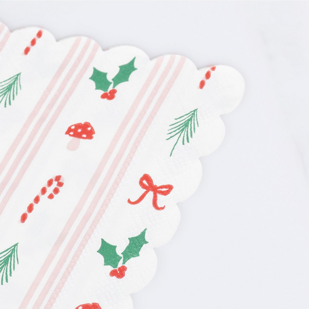 White napkin with Christmas-themed patterns including holly leaves, berries, candy canes, and bows on a white background.