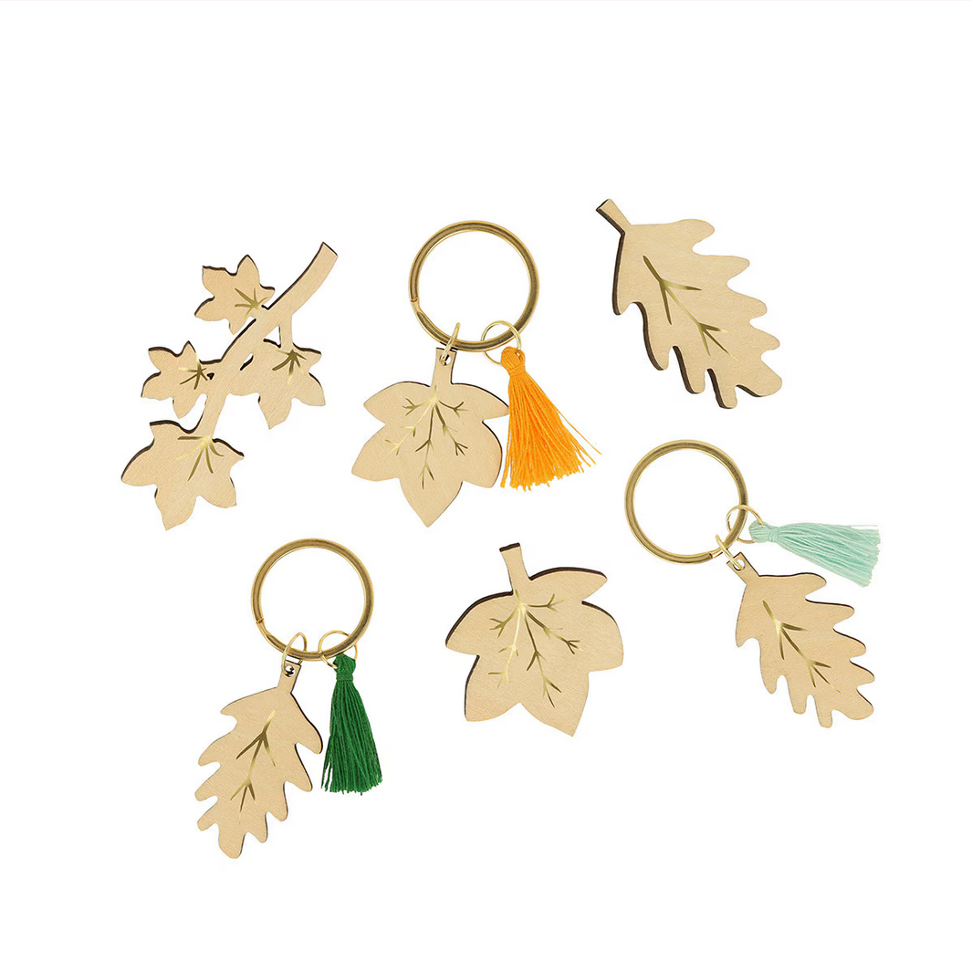 Set of leaf-shaped keychains with colorful tassels on a white background