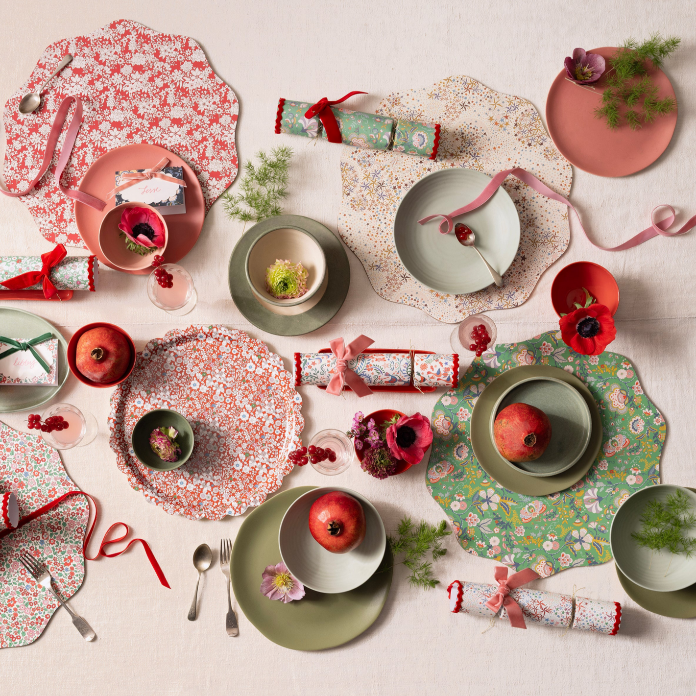 Decorative table setting with floral plates, pomegranates, and crackers on a light background