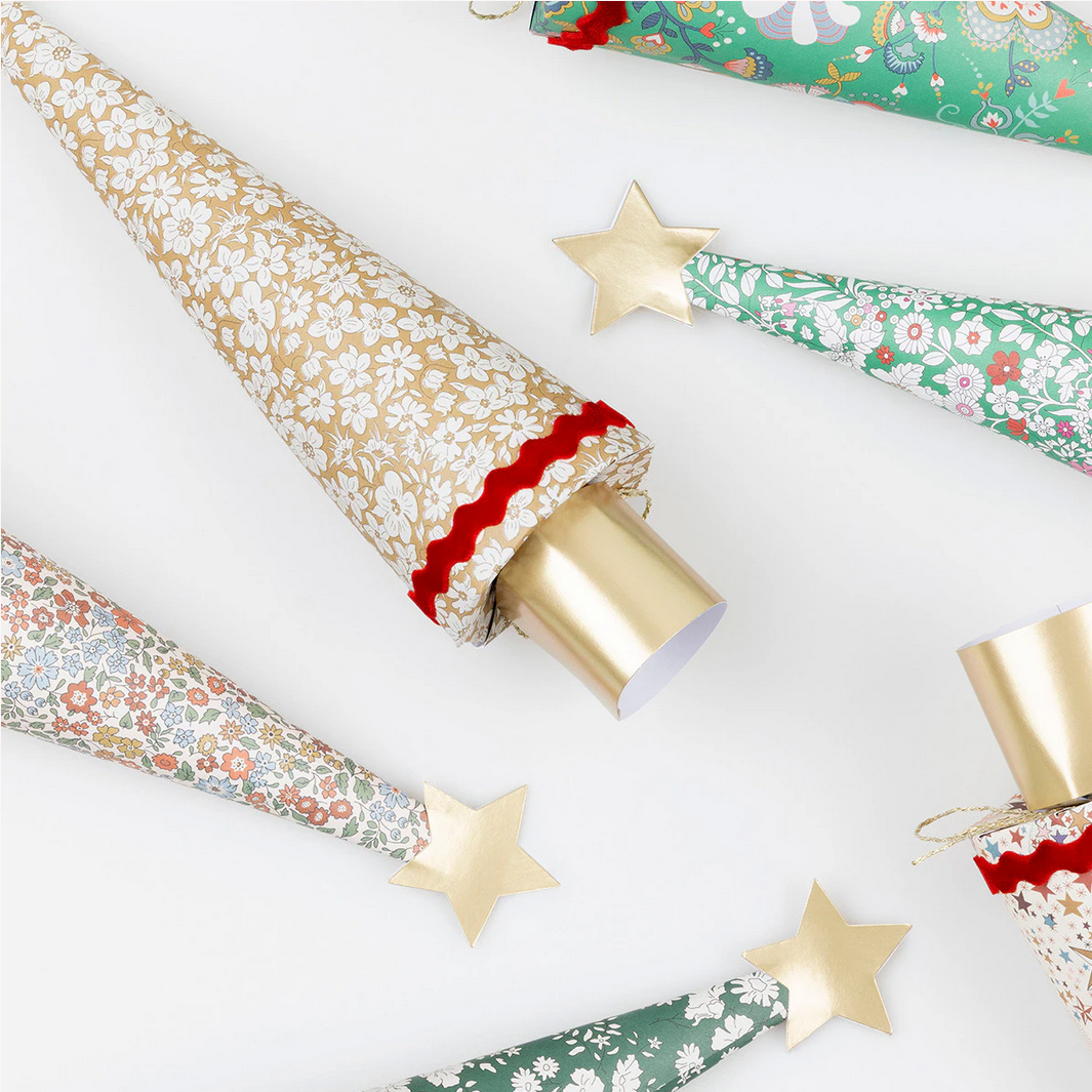 Rolls of floral-patterned wrapping paper with gold stars on a white background