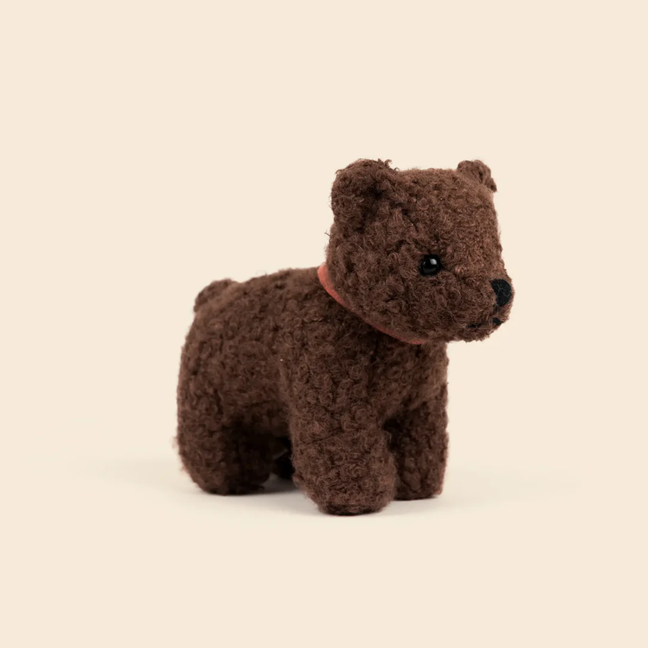 Small brown bear plush toy on a beige background