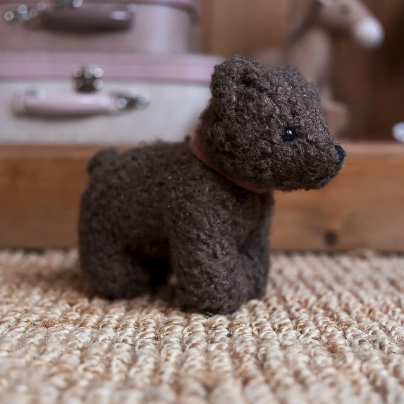 Small brown knitted toy bear on a textured surface with a blurred background