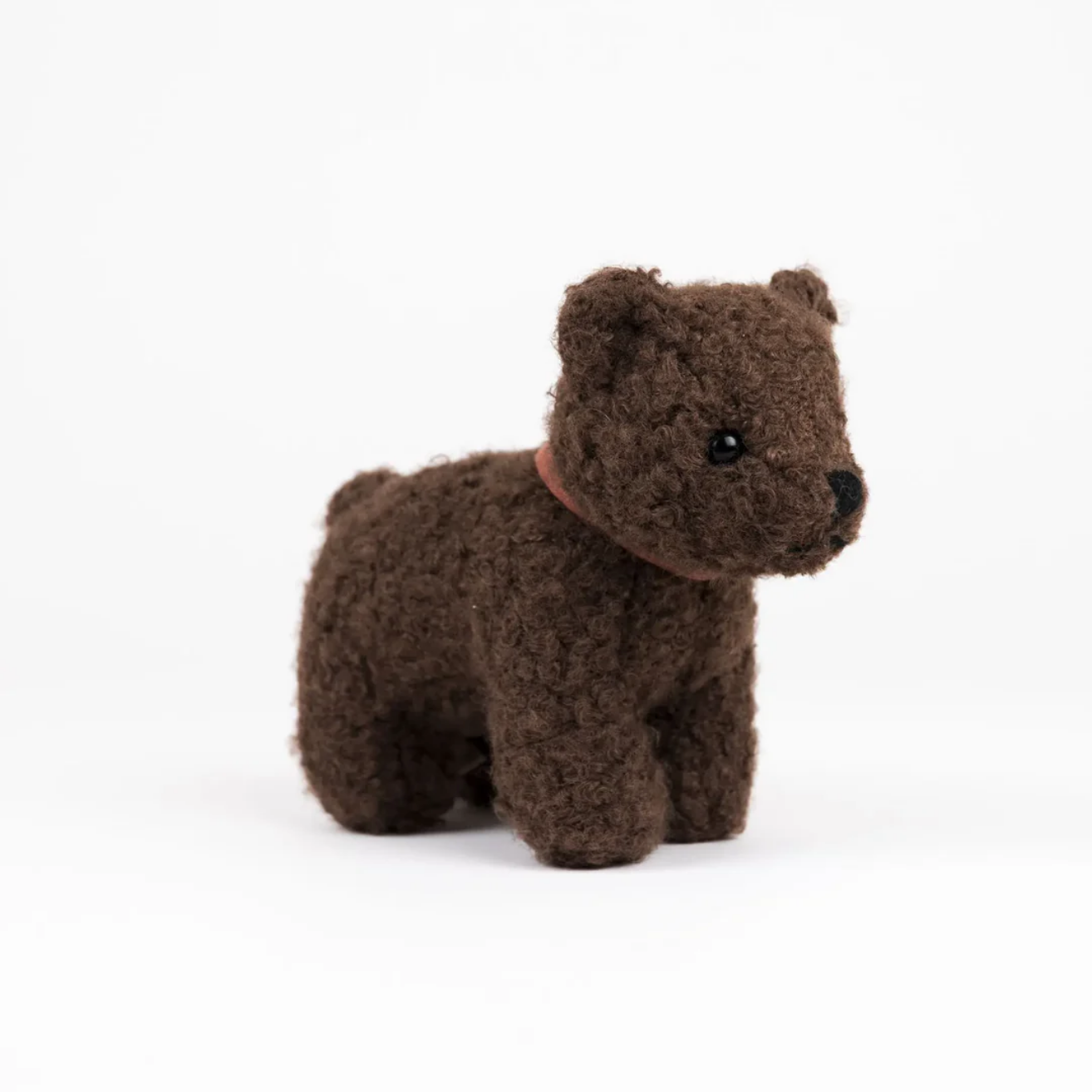 Small brown plush dog toy on a white background