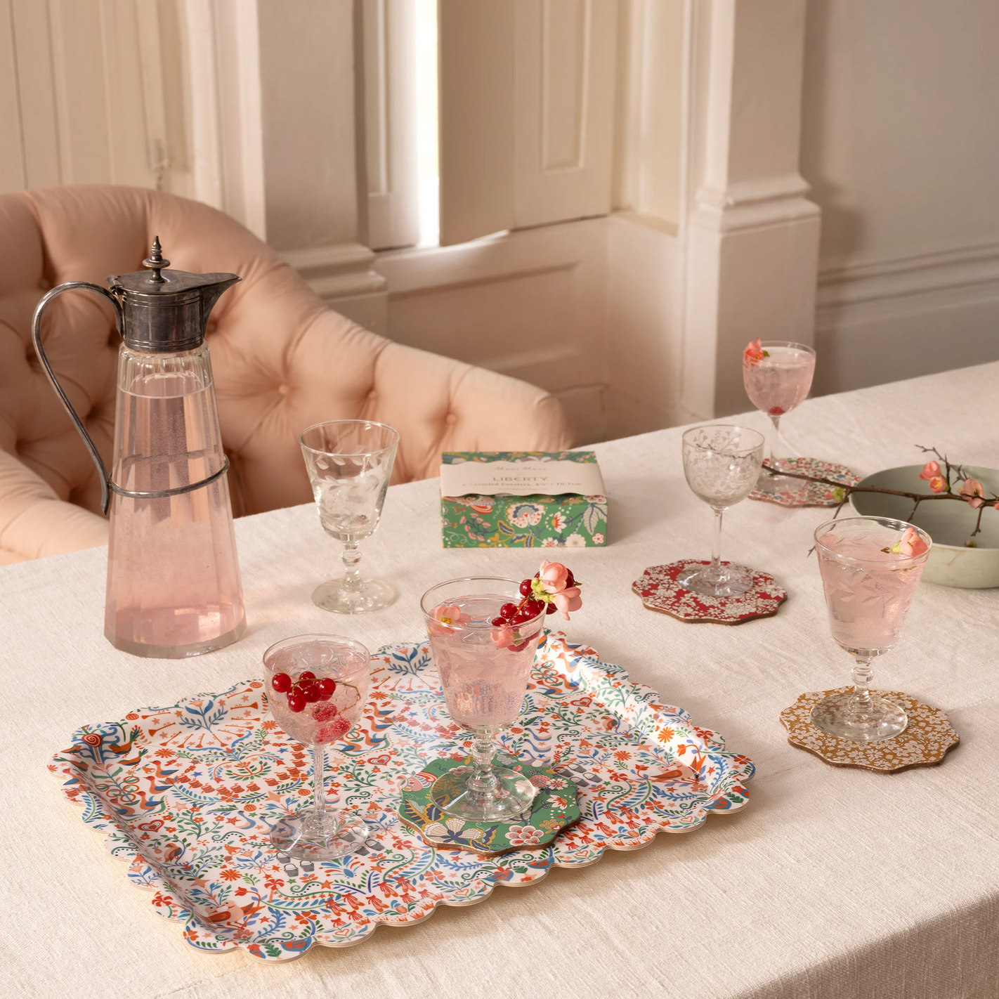 Table setting with glasses, a pitcher, and decorative platters on a white tablecloth.