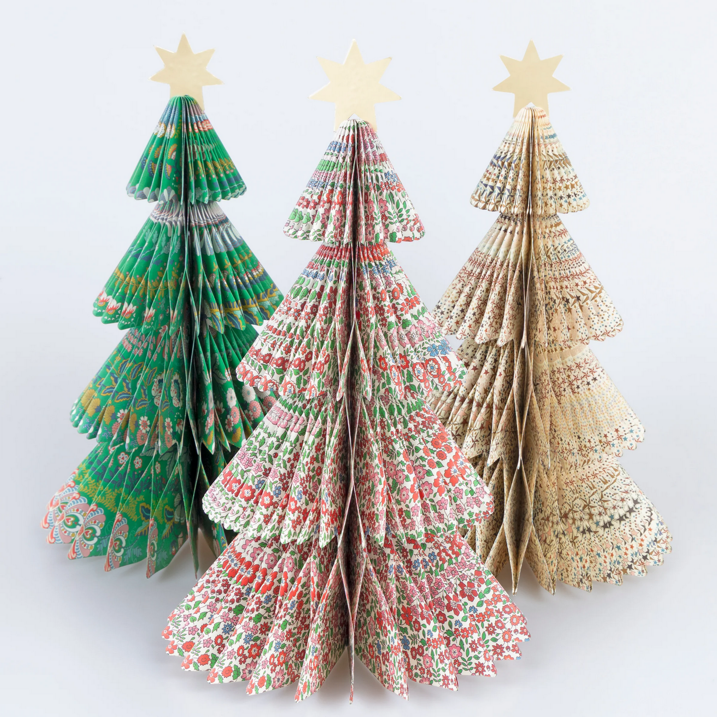 Three paper Christmas trees with star toppers on a white background