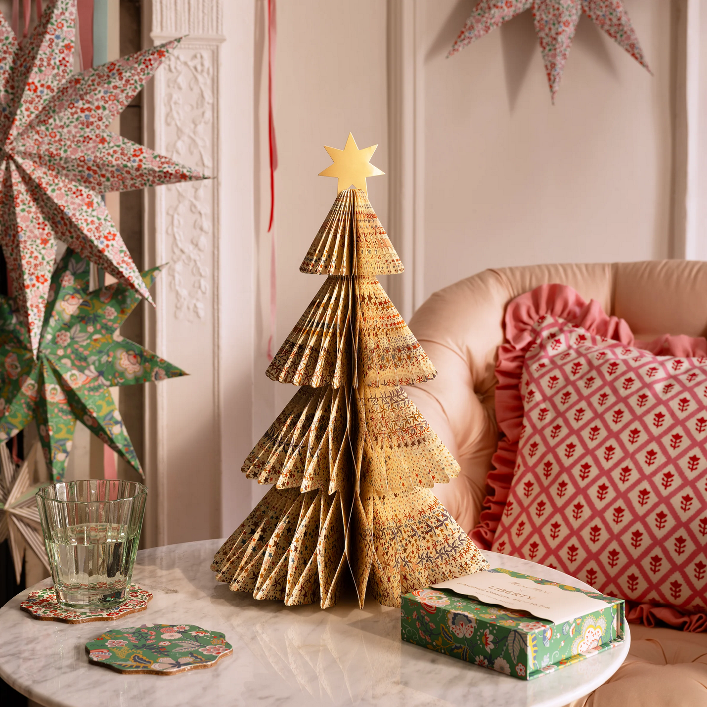Decorative paper Christmas tree on a table with festive decorations in the background