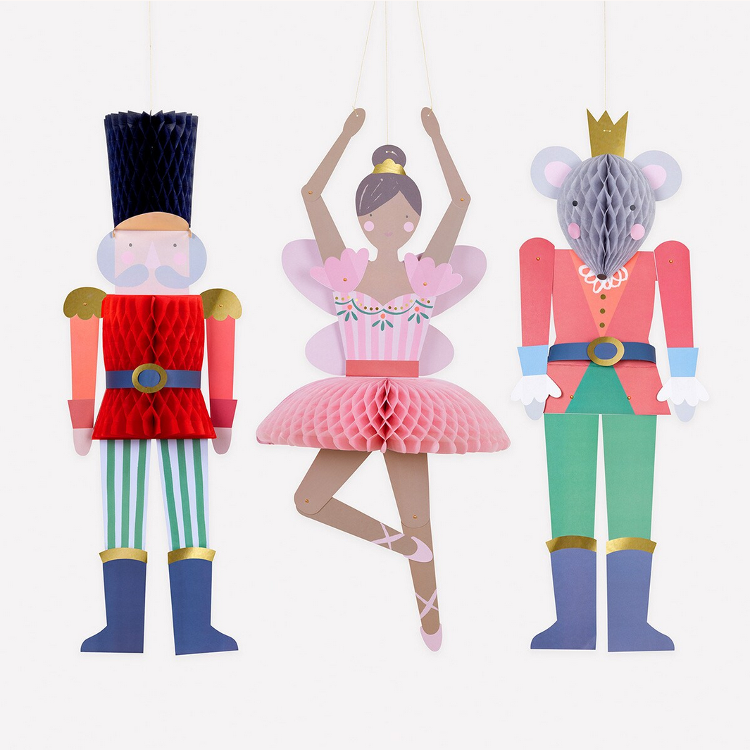 Decorative paper cutouts of a nutcracker, ballerina, and mouse king on a white background