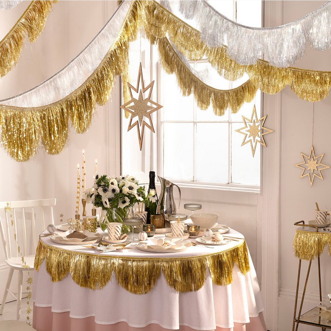 Decorated dining room with gold and white tablecloth, festive decorations, and a window.