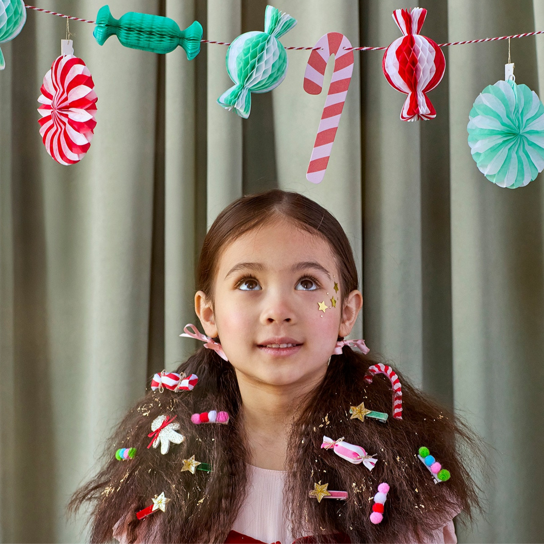 Young girl with candy-themed hair accessories in front of a candy-themed garland.