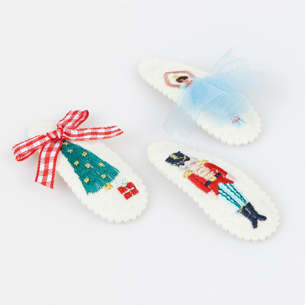 Decorative Christmas-themed hair clips with a Nutcracker design on a white background.