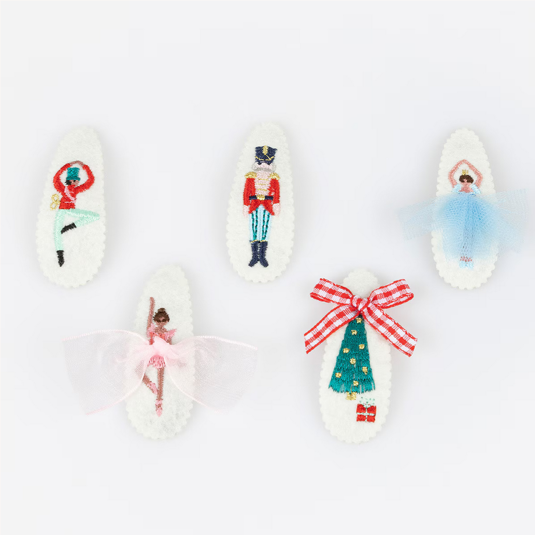 Decorative spoons with embroidered designs of a ballerina, nutcracker, and other festive elements on a white background.