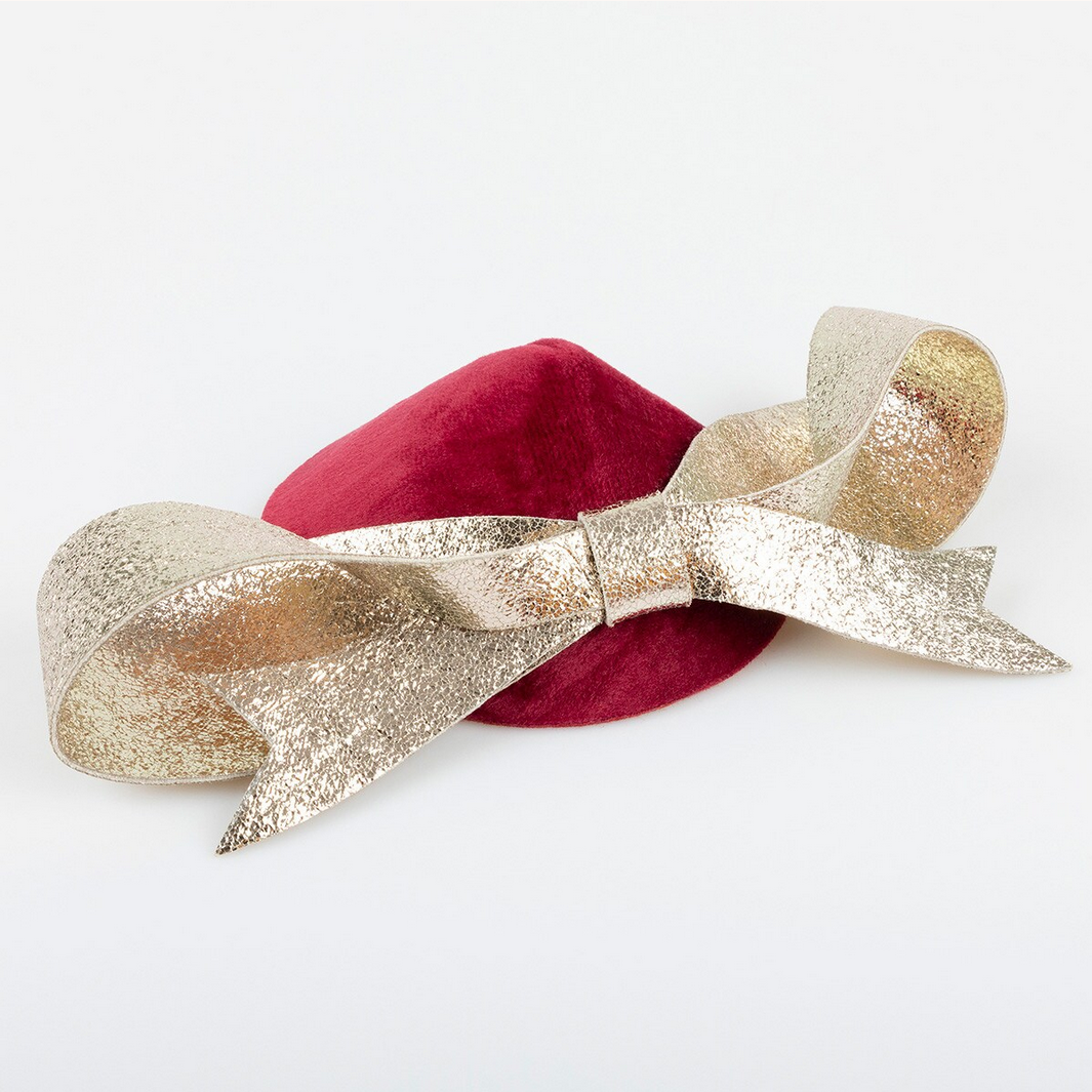 Red hat with a large gold glittery bow on a white background